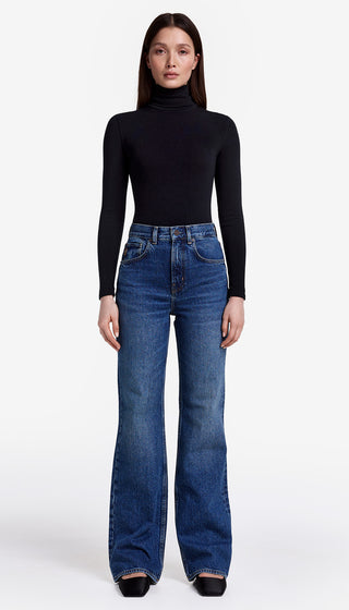 Woman wearing a black turtleneck and blue jeans on a white background