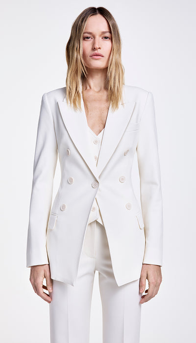 A model wearing a white single-breasted blazer with a peak lapel and double-breasted appearance, paired with a white pant.