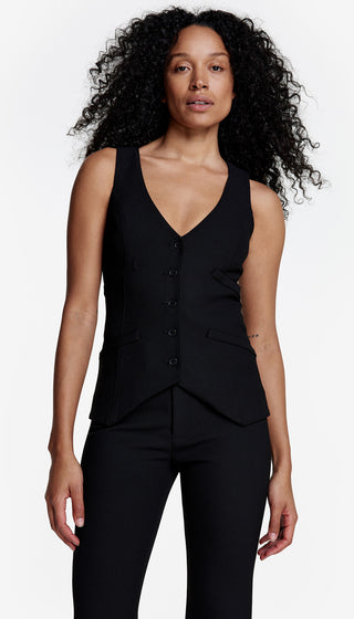 A woman wearing a black single-breasted stretch waistcoat with a deep V neckline, buttoned up the front, paired with black pants.