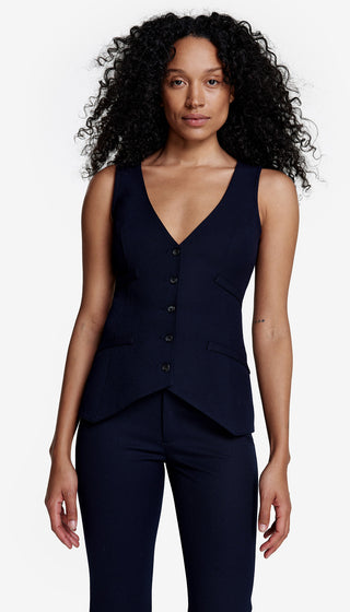 A woman wearing a deep navy single-breasted stretch waistcoat with a deep V neckline, buttoned at the front, paired with matching pants.