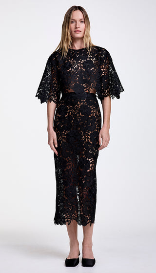 A model wearing a mid-rise, midi-length black lace pencil skirt with a coordinating top.
