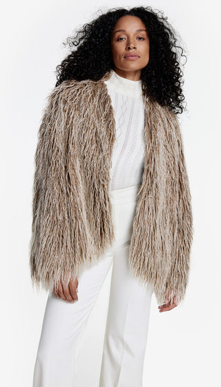 A model wearing a beige faux fur swing jacket over a white top, paired with white trousers.