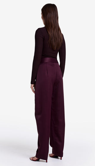 Person wearing a dark purple outfit with wide-leg pants on a white background