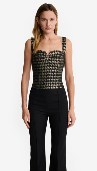 Woman wearing a patterned top and black pants on a white background