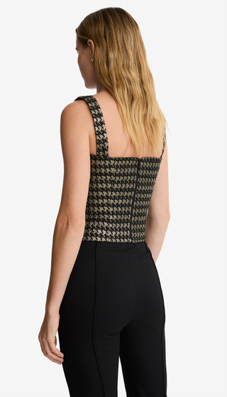 Woman wearing a patterned top and black pants on a white background