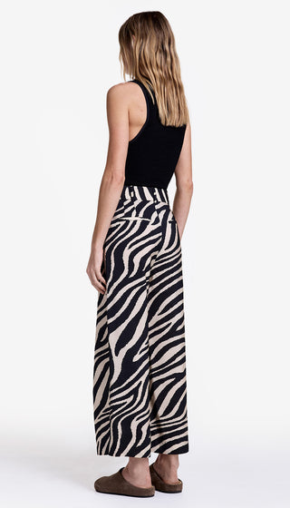 Woman wearing a black sleeveless top and zebra print pants on a white background