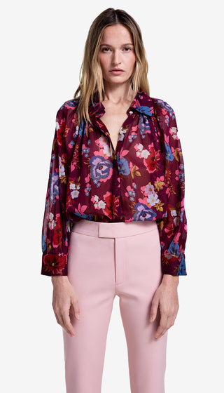 Woman wearing a colorful floral blouse and pink pants on a white background