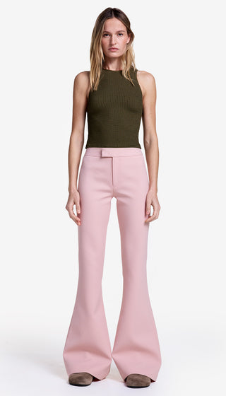 Woman wearing a green sleeveless top and pink flared pants on a white background