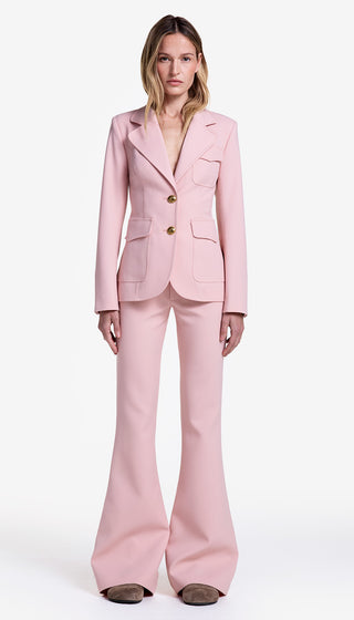 Woman wearing a pink suit with gold buttons on a white background