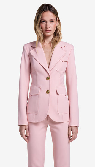 Woman wearing a pink suit with gold buttons on a white background