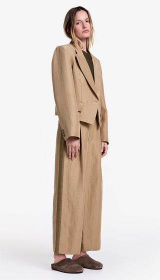 Woman wearing a long beige coat over a black top on a white background