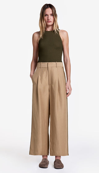 Woman wearing a green sleeveless top and beige wide-leg pants on a white background