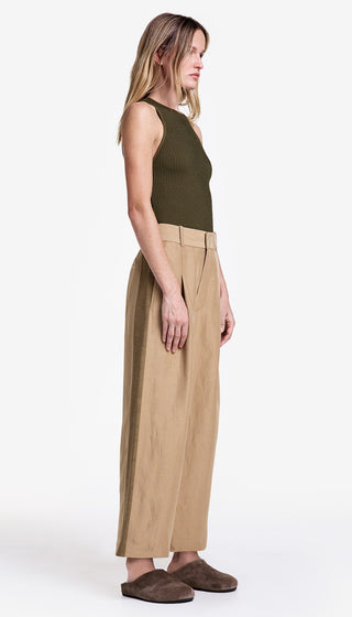 Woman wearing a green sleeveless top and beige wide-leg pants on a white background