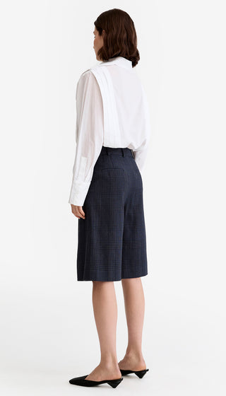 Woman wearing a white blouse and navy skirt on a white background