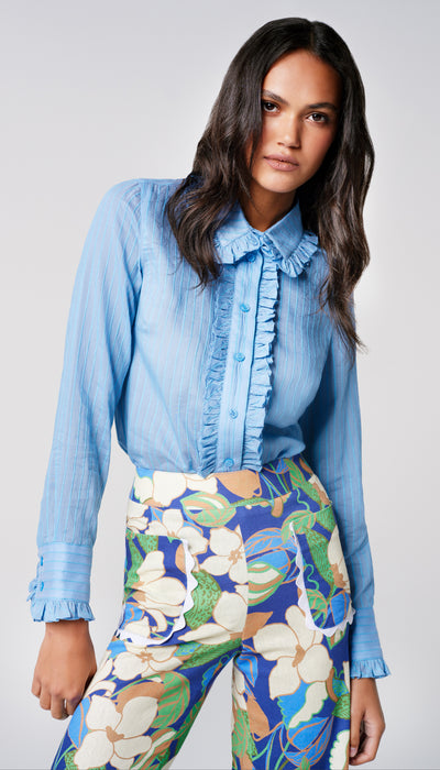A woman wearing a blue blouse with ruffles