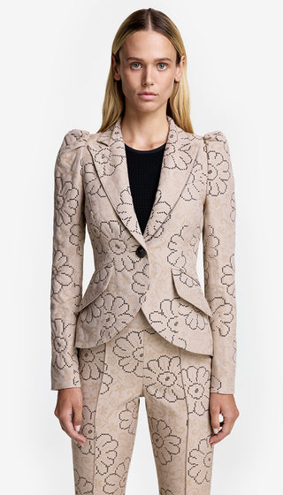A model wearing a beige blazer with a floral pattern, featuring pouf sleeves and a single button closure.