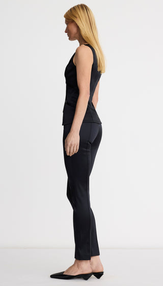 Woman wearing a black sleeveless top and pants on a white background