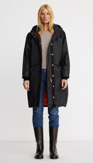 Person wearing a black raincoat with a hood on a white background