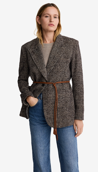 Woman wearing a patterned coat with a belt on a white background