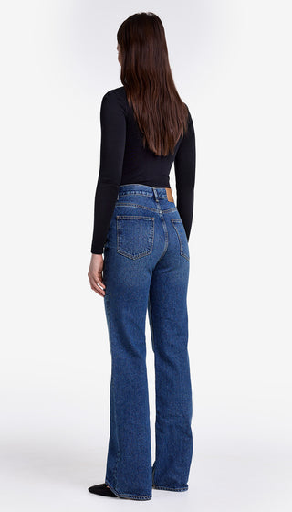 Person wearing blue jeans and a black top on a white background