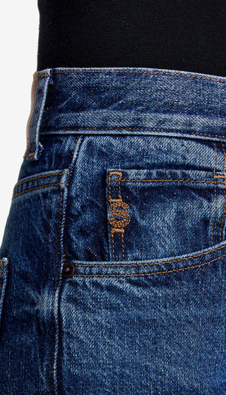 Close-up of blue jeans with a brand logo on the back pocket against a white background