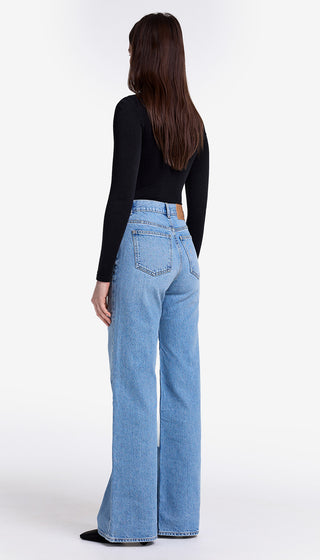 Person wearing blue jeans and a black top on a white background