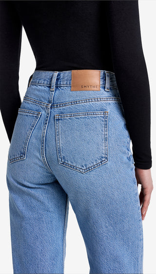 Blue jeans with a brand label on the back pocket against a white background