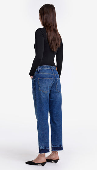 Person wearing blue jeans and a black top on a white background