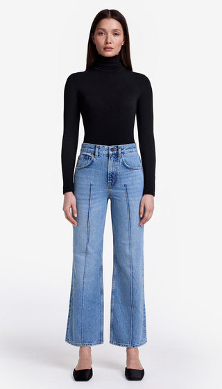 Person wearing a black turtleneck and blue jeans on a white background