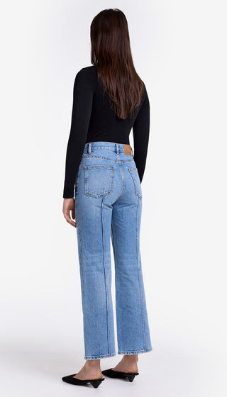 Person wearing light blue jeans and a black top on a white background