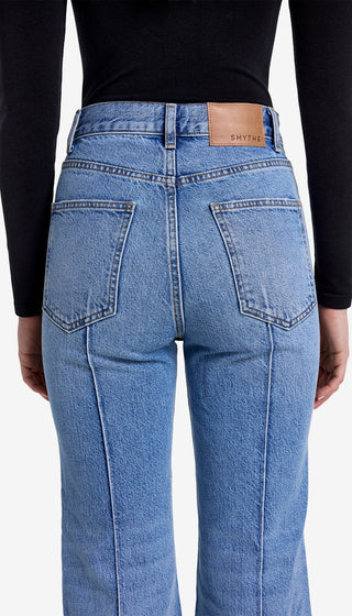 Blue jeans with a brand label on the back pocket against a white background