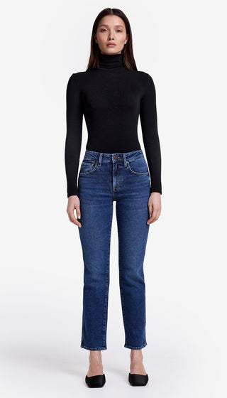 Woman wearing a black turtleneck and blue jeans on a white background