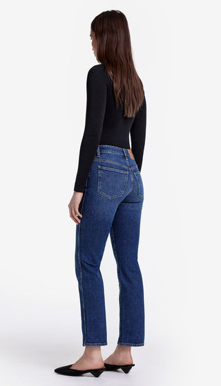 Woman wearing blue jeans and a black top on a white background