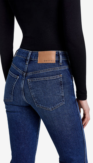 Person wearing blue jeans with a visible brand label on a white background