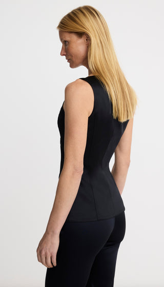 Person wearing a black sleeveless top and pants on a white background