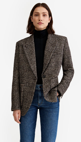 Person wearing a patterned blazer over a black turtleneck and blue jeans on a white background