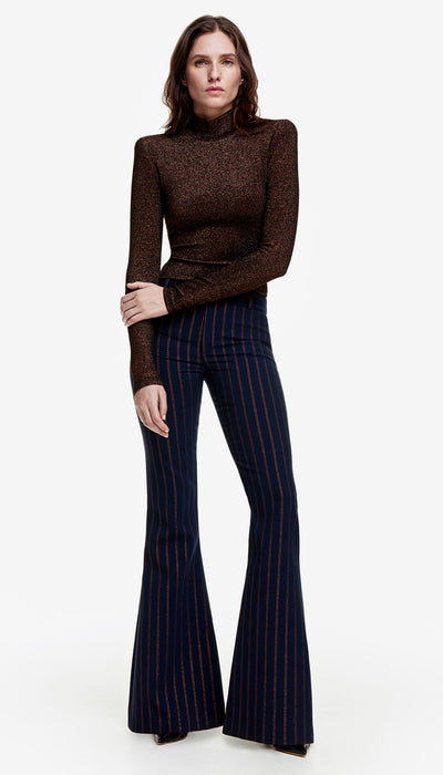 A person wearing a navy copper pinstripe bootcut pant and a brown turtleneck top.
