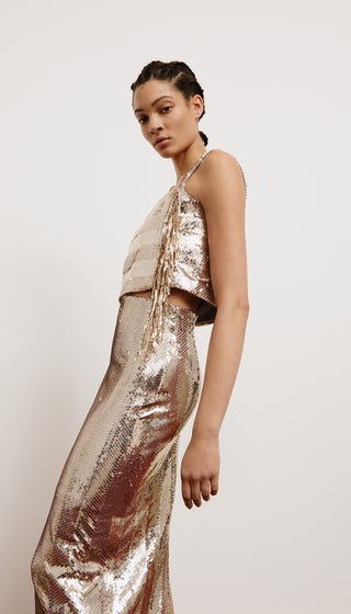 Woman wearing a sparkling gold outfit against a plain background