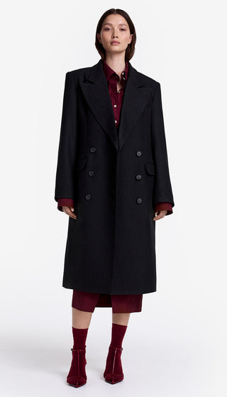 Person wearing a black coat and burgundy outfit on a white background