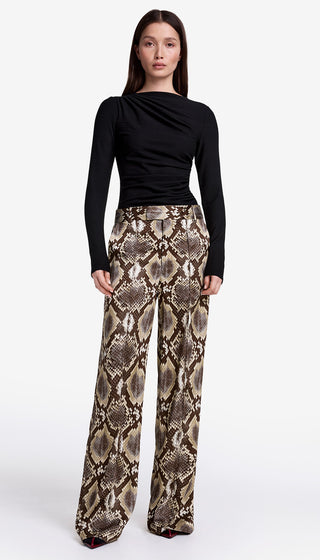 Woman wearing a black top and snake print pants on a white background
