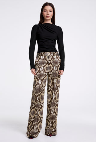 Woman wearing a black top and snake print pants on a white background