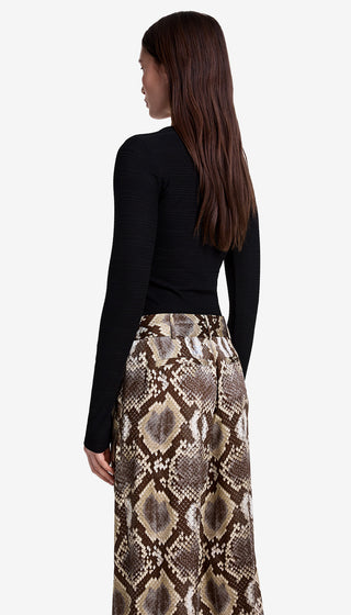 Woman wearing a black long-sleeve top and snake print skirt on a white background