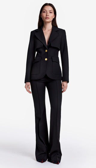 Woman wearing a black suit with gold buttons on a white background