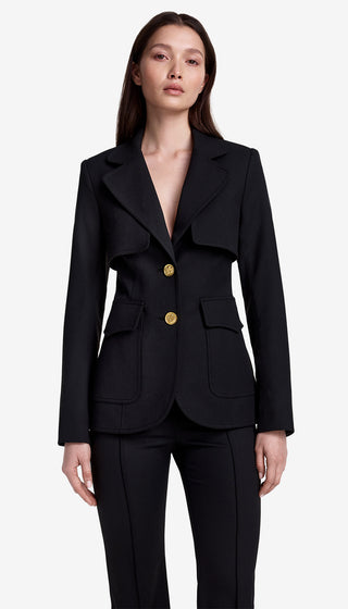Woman wearing a black suit with gold buttons on a white background