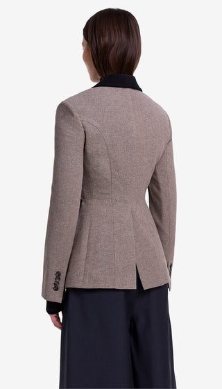 Person wearing a brown blazer and dark pants on a white background