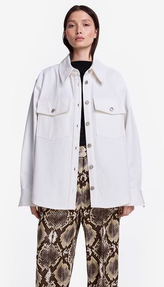 Person wearing a white jacket over a black shirt with snake print pants on a white background