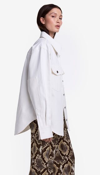 Woman wearing a white coat over a patterned skirt on a plain background