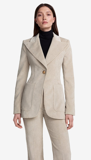 Woman wearing a beige suit with a black turtleneck on a white background
