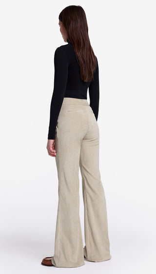 Woman wearing beige wide-leg pants and a black top on a white background