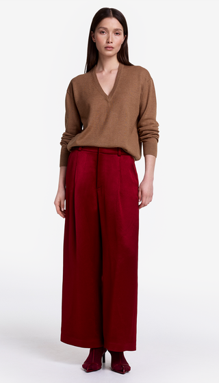 Woman wearing a brown sweater and red pants on a white background